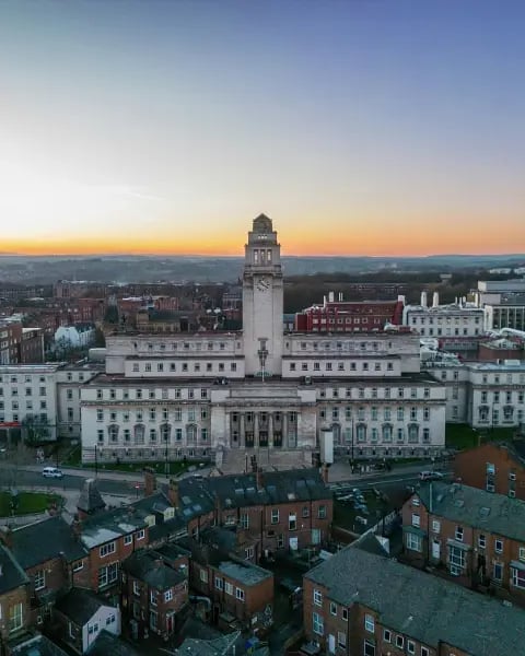 Parkinson Building at the University of Leeds with its clock tower, photographed from above at sunset with surrounding rooftops in the foreground.
